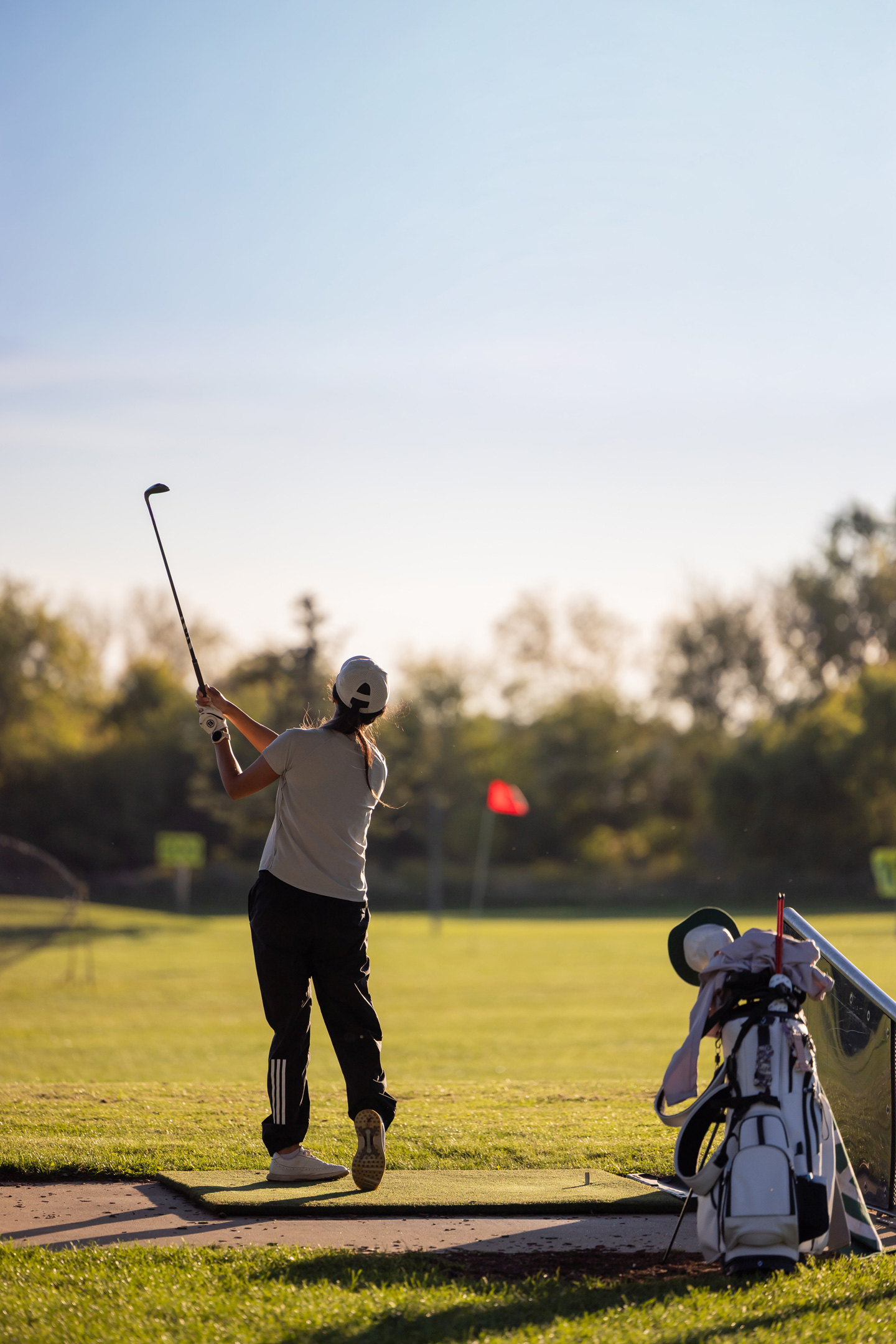 Golfer teeing off on a driving range at sunset