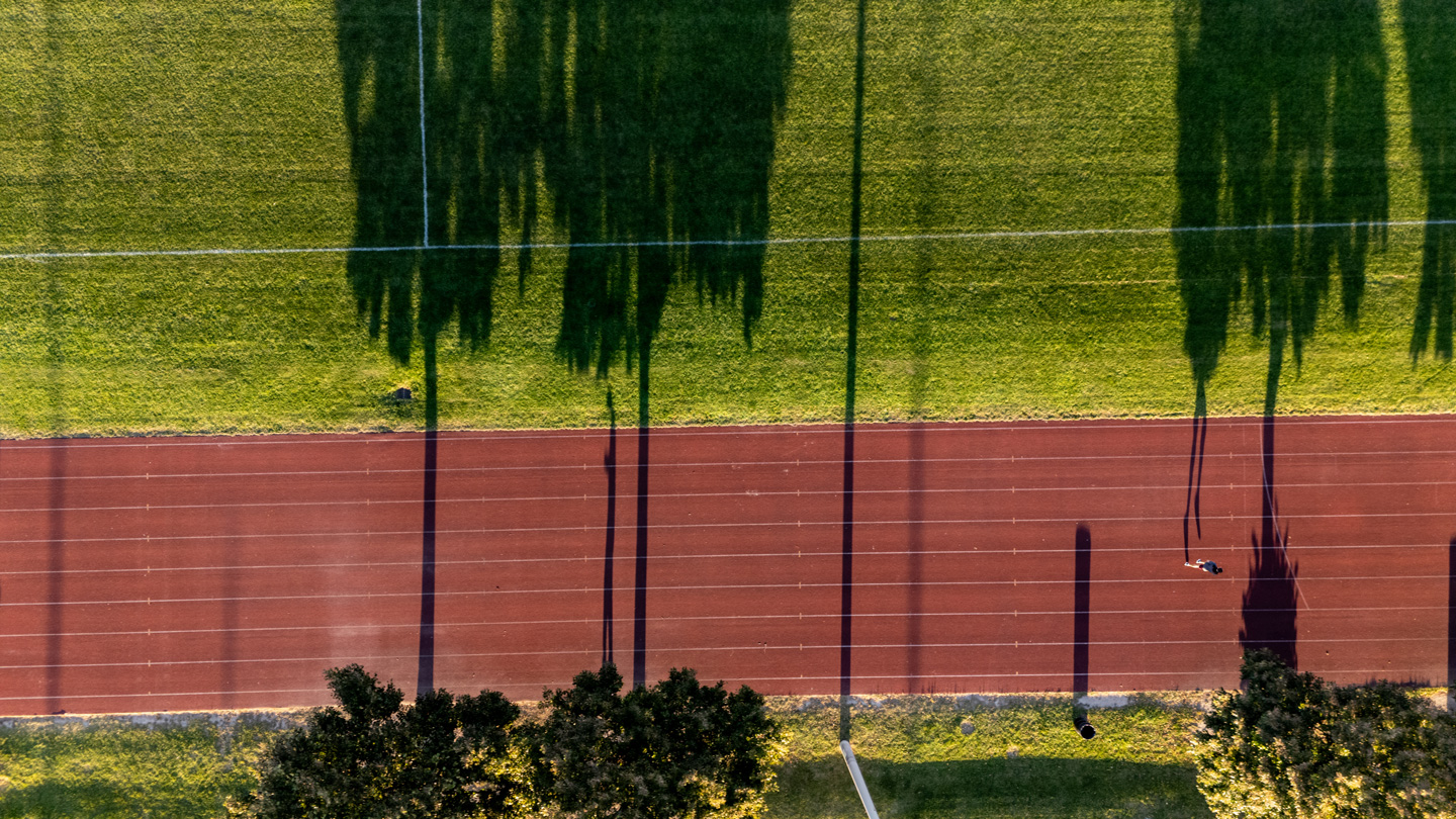 Running track with long tree shadows from above